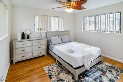 a bedroom with a bed and a dresser and windows at Charming 2BR Waterfront House in Fort Lauderdale