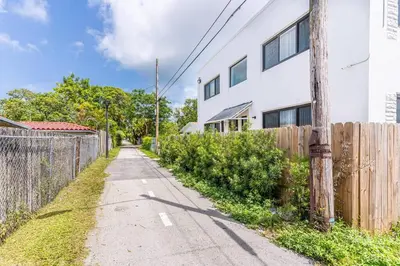 an empty street in front of a white building at Quiet Bright Apt 5min walking to Design District apt 6 in Miami