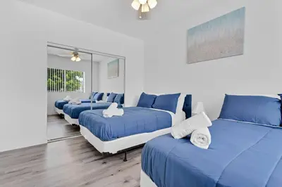 a room with four blue beds and a couch at Stylish Lux Apt 5 min walking to Design District apt 7 in Miami