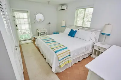 a white bedroom with a bed and two windows at Miami Pool Cottage, tropical garden paradise in Miami