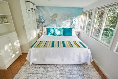 a bedroom with a large bed with blue pillows at Miami Pool Cottage, tropical garden paradise in Miami