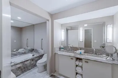 a bathroom with two sinks and a toilet and a tub at Stylish Oceanview Apartment Prime Location in Fort Lauderdale