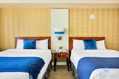 two beds in a hotel room with blue and white at Deluxe Studio Ocean View Premium Amenities in Sunny Isles Beach