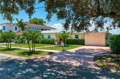 a house with a driveway and palm trees at Waterfront Pool & Amazing Location - WOW in Miami
