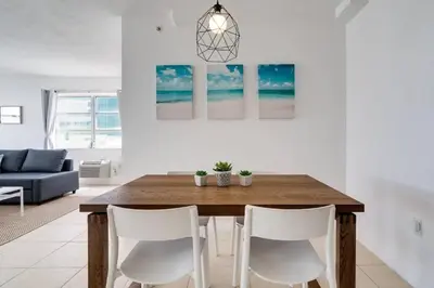 a dining room with a wooden table and white chairs at 1101- Luxurious 1BR & 2 Bath with City & Ocean Views in Miami Beach