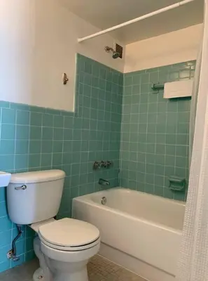 a bathroom with a white toilet and a green tiled wall at 1402- Oceanfront 1BR & 1 Bath Retreat with Stunning Views in Miami Beach