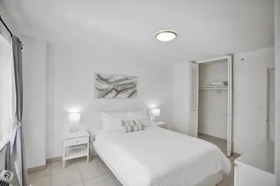 a white bedroom with a white bed and a mirror at 1506- 1BR & 1BA Retreat with Stunning Intracoastal Views in Miami Beach