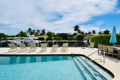 a swimming pool with chairs and a table and a boat at Fort Lauderdale Beach Oasis in Fort Lauderdale