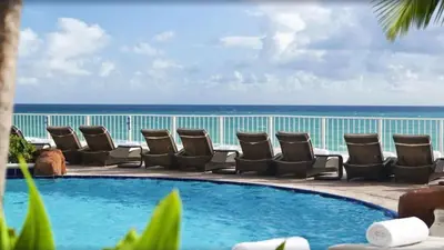 a pool with chairs and the ocean in the background at Luxury Bayfront Studio with Balcony Amazing Pool in Sunny Isles Beach