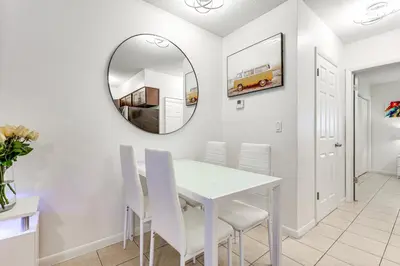 a dining room with a white table and chairs and a mirror at 2 Mi to Dtwn Hollywood Vibrant Pet-Friendly Condo in Hallandale Beach