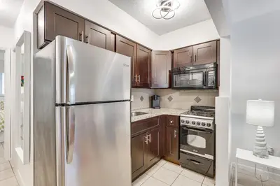 a kitchen with wooden cabinets and a stainless steel refrigerator at 2 Mi to Dtwn Hollywood Vibrant Pet-Friendly Condo in Hallandale Beach