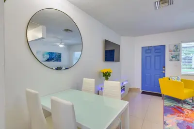 a dining room with a white table and a mirror at 2 Mi to Ocean Dog-Friendly Hallandale Beach Condo in Hallandale Beach