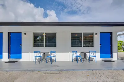 a group of blue chairs and tables in front of a building at 2 Mi to Ocean Dog-Friendly Hallandale Beach Condo in Hallandale Beach