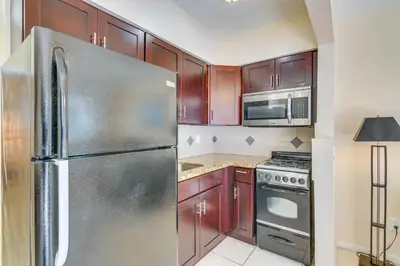 a kitchen with wooden cabinets and a stainless steel refrigerator at Pet-Friendly Hallandale Beach Condo Near Boardwalk in Hallandale Beach
