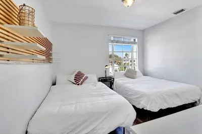 two beds in a white room with a window at Miami Beach Home, 7 guests, Steps from the beach in Miami Beach
