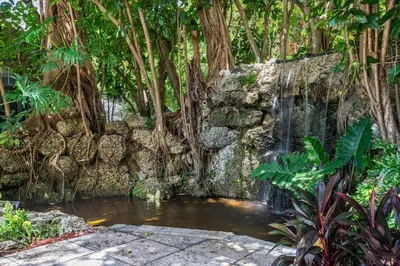 a waterfall in a garden next to a stone wall at The Palms Coconut Grove 1 bedroom condo includes parking in Miami