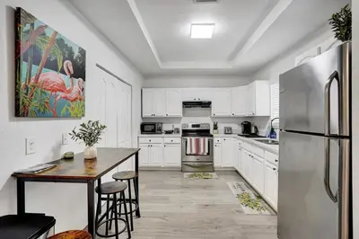 a kitchen with white cabinets and a table and a refrigerator at Beautiful Home in Maimi in Miami