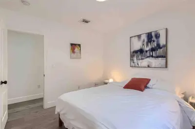 a bedroom with a white bed and a painting on the wall at Beautiful Home in Maimi in Miami
