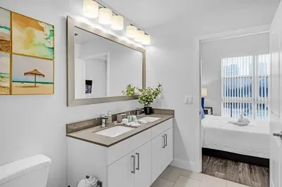 a bathroom with a sink and a mirror and a bed at Bright and Airy 2 Bed on Biscayne Blvd with Free Park in Miami