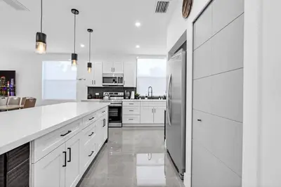 a kitchen with white cabinets and a stainless steel refrigerator at Paraiso House Pool 10 Ppl 6 mins Coconut Grove in Miami