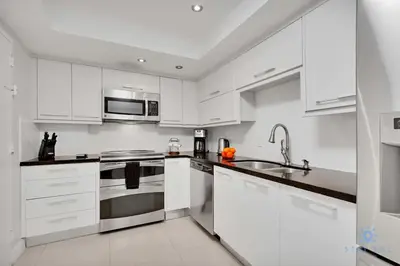 a white kitchen with stainless steel appliances and white cabinets at Beautiful apartment with pool and gym in Hollywood