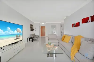 a white living room with a couch and a tv at Beautiful apartment with pool and gym in Hollywood