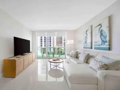 a white living room with a white couch and a tv at Luxe Hollywood Beachfront Condo in Hollywood