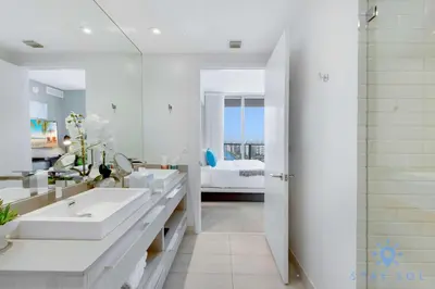 a white bathroom with two sinks and a bedroom at High Floor 3BR - 2BA - Resort Fees & Parking Incl in Hollywood