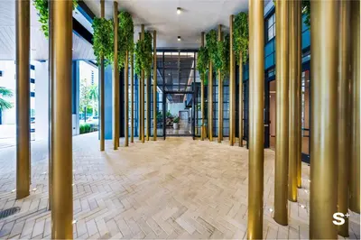 a hallway with gold columns and plants in a building at Modern 1BD & Den With City Views in Miami