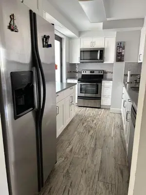 a stainless steel refrigerator in a kitchen with wooden floors at Beautiful Water View Golden Isles in Hallandale Beach
