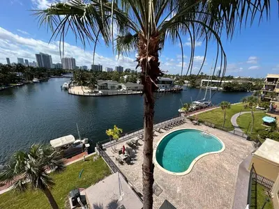 a palm tree next to a river with a swimming pool at Beautiful Water View Golden Isles in Hallandale Beach