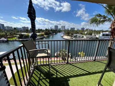 a balcony with two chairs and a view of a river at Beautiful Water View Golden Isles in Hallandale Beach