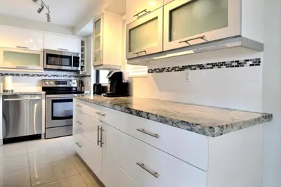 a kitchen with white cabinets and granite counter tops at Golden Isles # 509 in Hallandale Beach