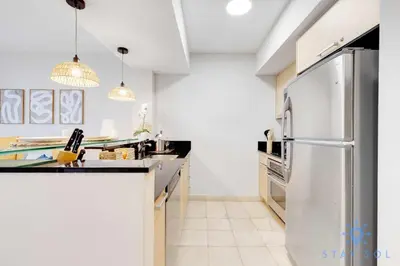 a kitchen with white walls and a stainless steel refrigerator at Amazing Apartment Oceanview Beautiful Amenities in Sunny Isles Beach
