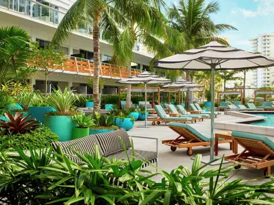 a hotel patio with chairs and umbrellas and a pool at The Gates Hotel South Beach in Miami Beach