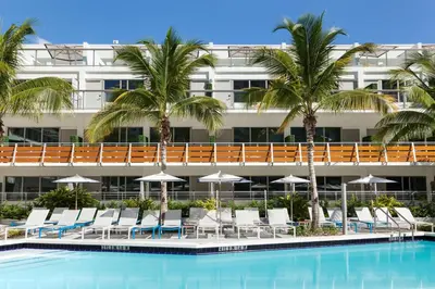 a hotel with a pool and chairs and palm trees at The Gates Hotel South Beach in Miami Beach