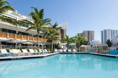 a large swimming pool in front of a building with palm trees at The Gates Hotel South Beach in Miami Beach