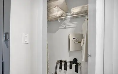 a white bathroom with a closet with a towel at Find Tranquility in the Grove in Miami