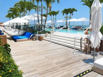 a pool with chairs and umbrellas on a resort at Romantic-5 star-1BR-Oceanfront-Balcony-South-Beach in Miami Beach
