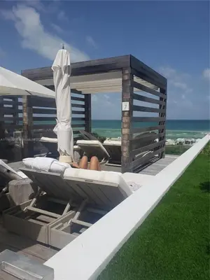 a patio with a couch and an umbrella and the ocean at Romantic-5 star-1BR-Oceanfront-Balcony-South-Beach in Miami Beach