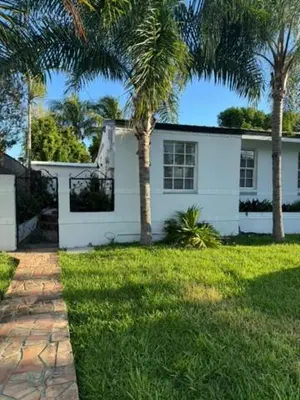 a white house with palm trees in the yard at Cozy Corner in Miami
