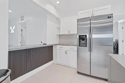 a white kitchen with a stainless steel refrigerator at Villa Verde - Your Exclusive Luxury Escape with Private Pool and Mini Golf in Miami