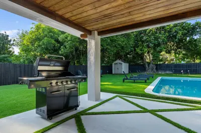 a barbecue grill on a patio next to a swimming pool at Villa Verde - Your Exclusive Luxury Escape with Private Pool and Mini Golf in Miami