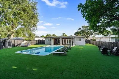a backyard with a swimming pool and chairs on the grass at Villa Verde - Your Exclusive Luxury Escape with Private Pool and Mini Golf in Miami