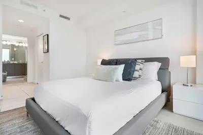 a white bedroom with a large white bed with pillows at La Central- CityPlace Doral and across from a Park in Miami