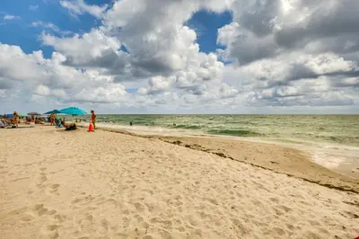 a group of people on a beach with an umbrella at Hollywood Condo with Beach Access - Walk to Shore! in Hollywood