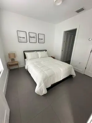 a white bedroom with a large bed and three pictures on the wall at Charming House at Miami's Heart in Miami
