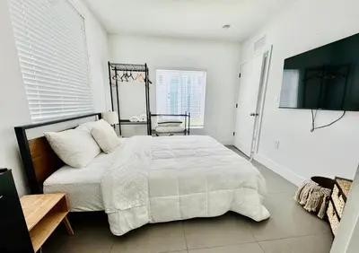a white bedroom with a bed and a television at Charming House at Miami's Heart in Miami