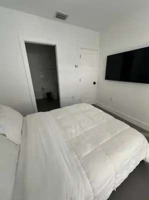 a bedroom with a white bed and a flat screen tv at Charming House at Miami's Heart in Miami