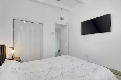 a white bedroom with a bed and a flat screen tv at Fort Lauderdale Home near Nightlife and Beach in Fort Lauderdale